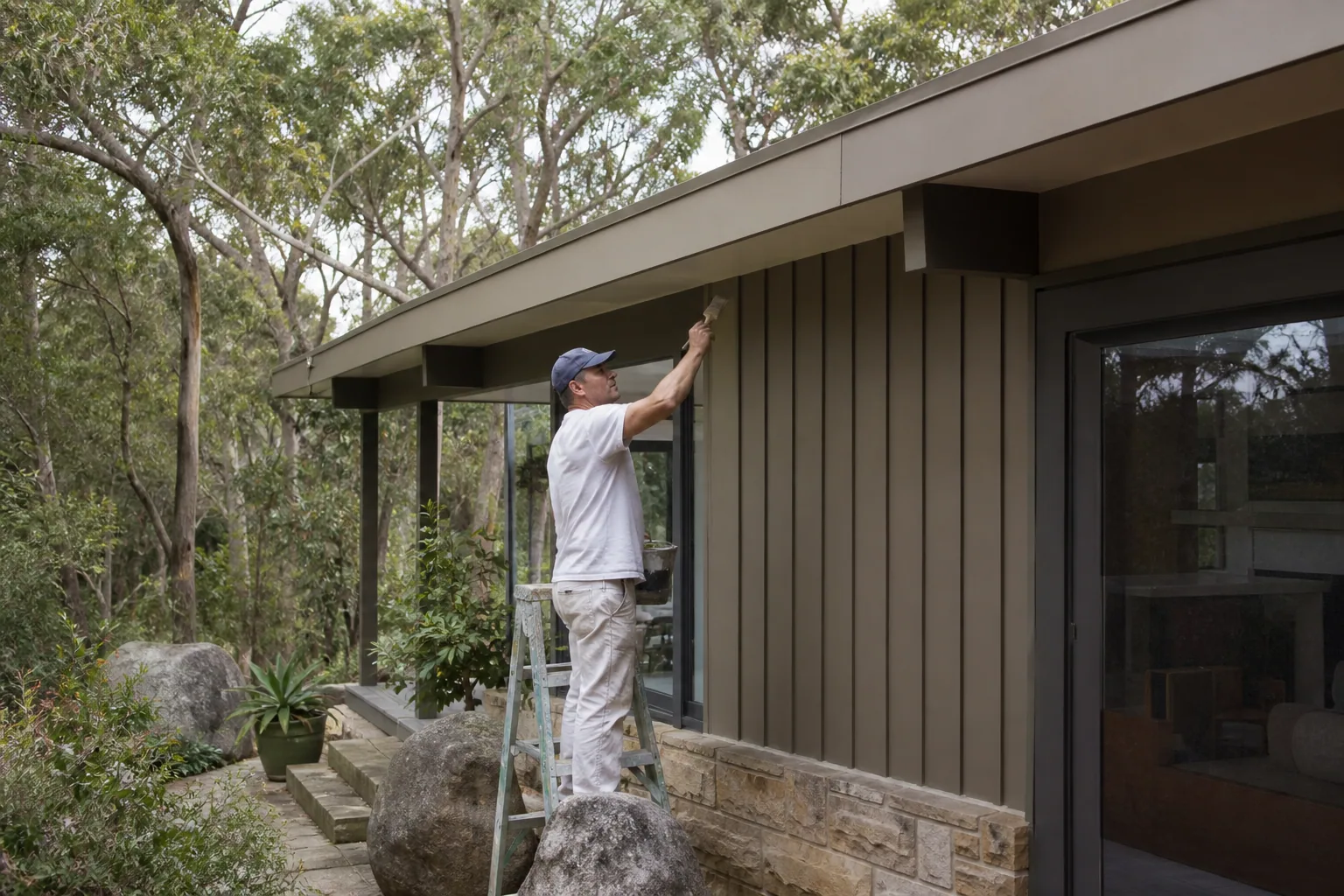 Painter coating a Campbells Bay clifftop home